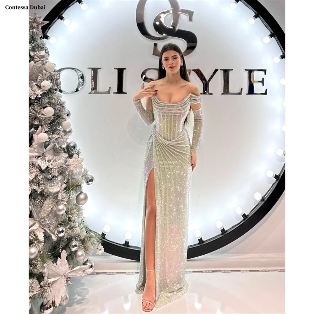 فستان كونتيسا دبي مخصص للحفلات الراقصة باللون الفضي اللامع مع أكمام مكشوفة الأكتاف من فيستدوس دي نوش، فستان رسمي بفتحة عالية
